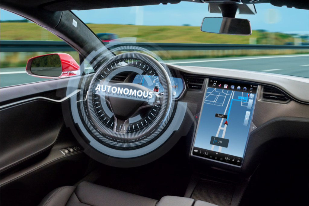 A car interior showing an empty driver’s seat with a digital interface reading "AUTONOMOUS" on the steering wheel and a navigation screen displaying a map route.