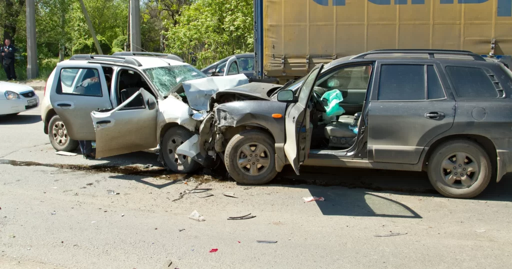Two SUVs with significant front-end damage after a head-on collision, airbags deployed, and debris scattered on the road.
