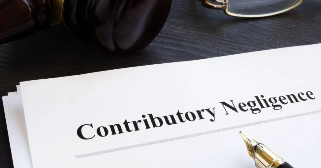 A document titled "Contributory Negligence" on a desk next to a pen, gavel, and eyeglasses.